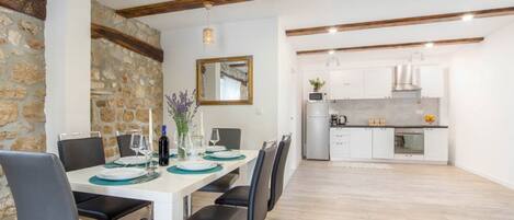 A modern kitchen with white cabinets, a built-in oven, and a stainless steel range hood.