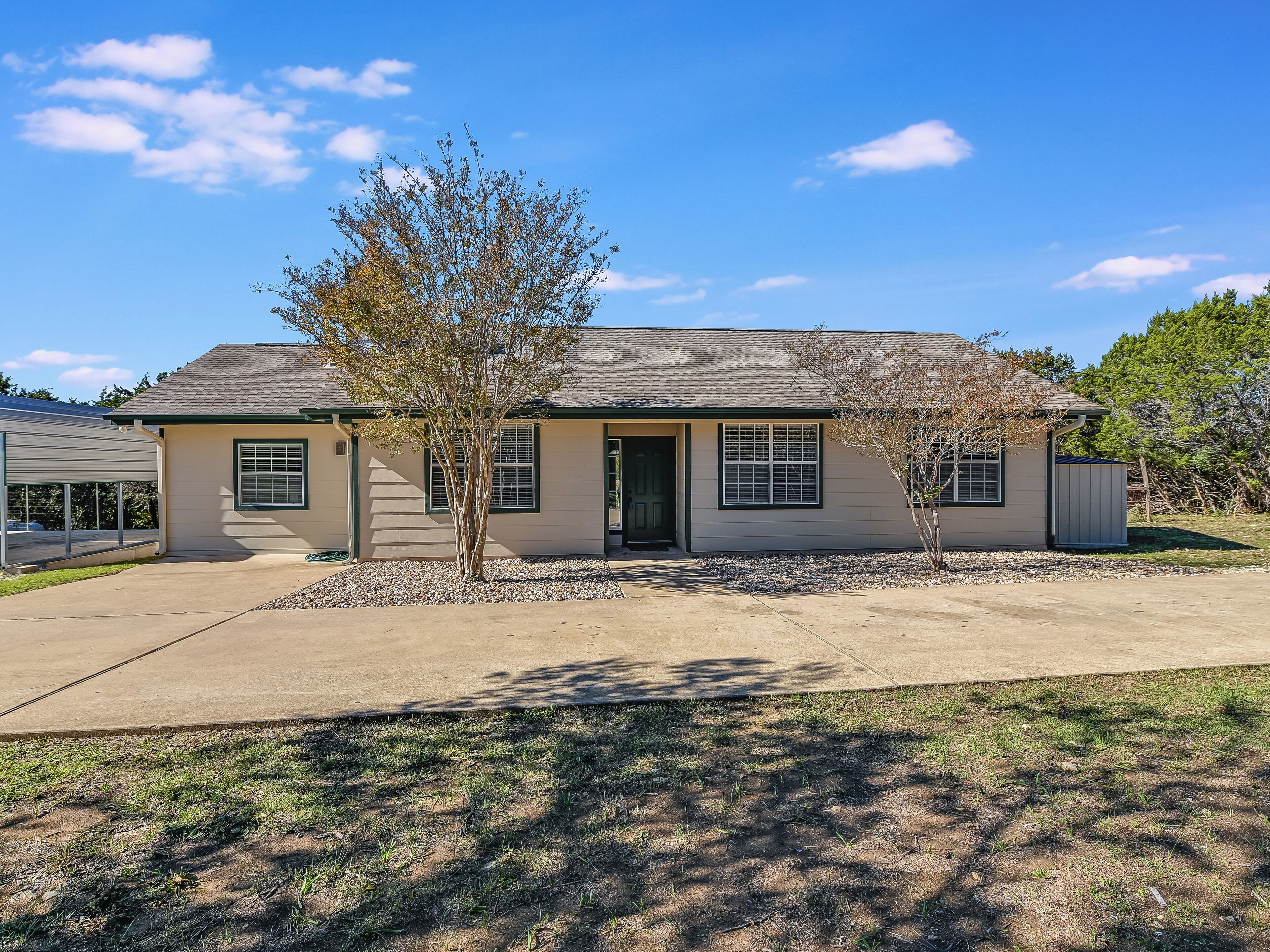 A single-story house with a garage, a front door, and a small tree in the front yard.