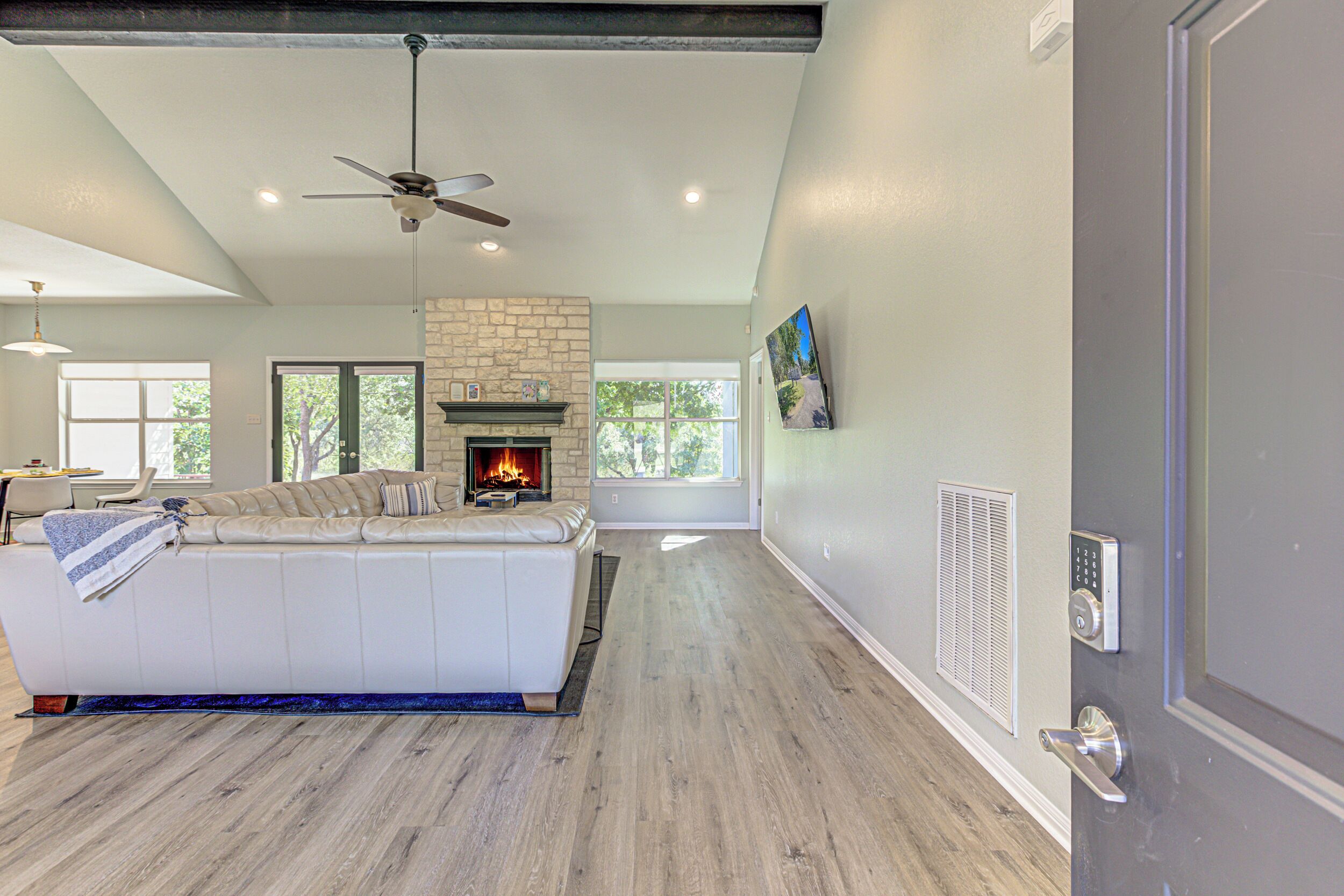 A spacious living room with a white sofa, a fireplace, and a ceiling fan.