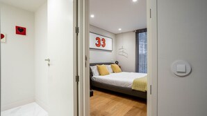 A modern bedroom with a bed, a wall-mounted number '33', and a window with blinds.