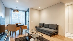A modern living room with a sofa, coffee table, and dining area.