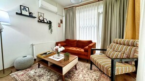 A living room with a sofa, armchair, coffee table, and a hanging light fixture. - Modern Furnished Historical House (İstanbul)