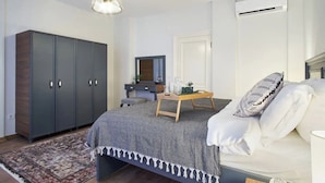 A bedroom with a bed, a wardrobe, a desk with a mirror, a hanging light fixture, and an air conditioning unit. - Modern Furnished Historical House (İstanbul)