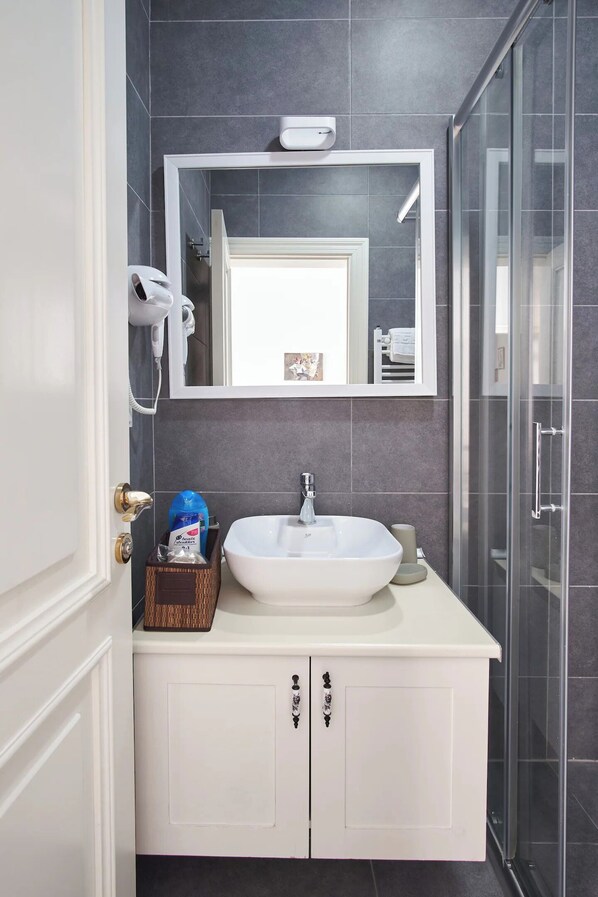 A bathroom with a white sink, a mirror above it, and a glass shower door.
