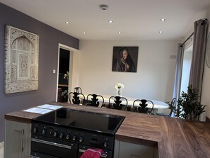 Una cucina moderna con piano cottura integrato, forno e zona pranzo con tavolo e sedie.