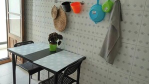 Un coin repas avec une table et des chaises, une plante en pot et des ustensiles de cuisine accrochés au mur.