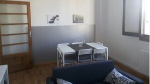 Une pièce comprenant une table à manger, des chaises, un canapé, une porte en bois et une fenêtre.