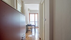 En hall som leder till en matplats med ett bord och stolar, en skjutdörr i glas och en lampa.
