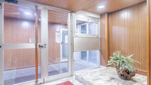 En hotellentrél med en dörr av trä, en krukväxt och ett golv av marmor.