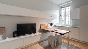 A modern kitchen with a flat-screen TV, wooden countertop, and a window with decorative iron bars. - Italianway Easy - Gentilino 15 (Milano)