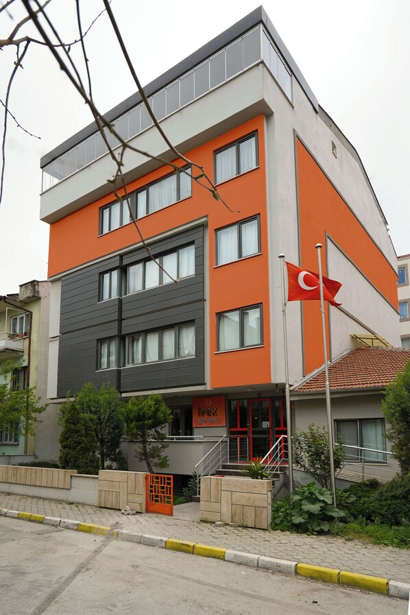 A multi-story building with a modern design, featuring a prominent orange facade and a flagpole with a flag.