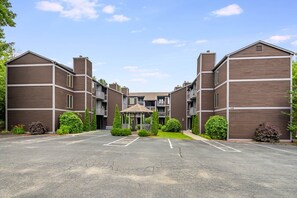 A multi-story residential building with a central courtyard, balconies, and a parking lot. - Downtown 1st Floor | Walk to Main St + Fireplace (Blowing Rock)