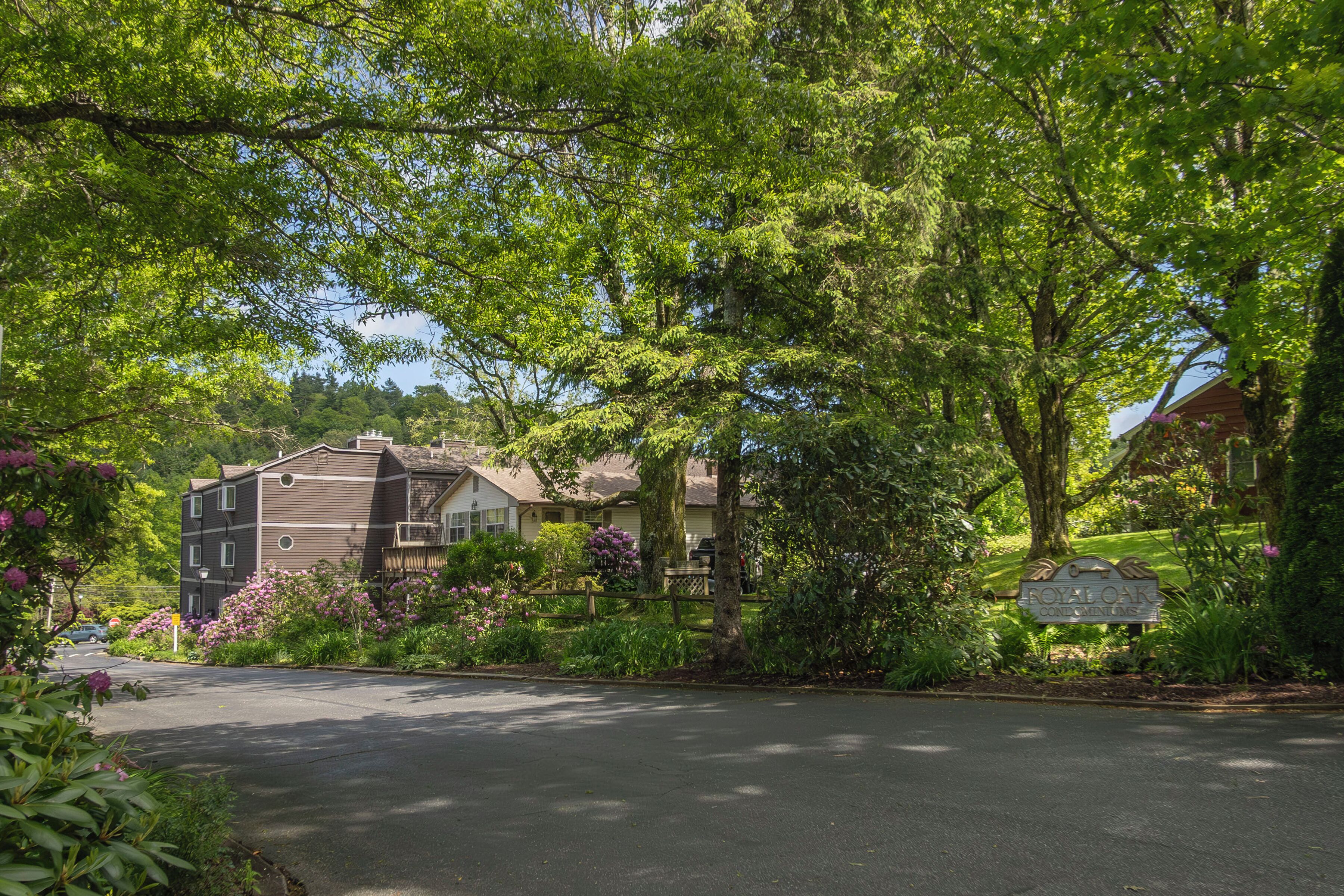 Une rue résidentielle bordée de maisons, avec une enseigne indiquant « RÉSIDENCE ROYALE OAK », et une végétation luxuriante.