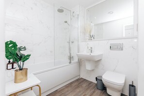 Enjoy a refreshing shower in the bathroom, which features a glass-enclosed shower, pedestal sink, and toilet.