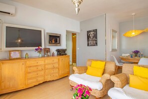 Un salon comprenant un canapé, un meuble en bois, un téléviseur et un miroir fixé au mur.
