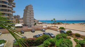A coastal building with a parking area, a beach, and clear skies.