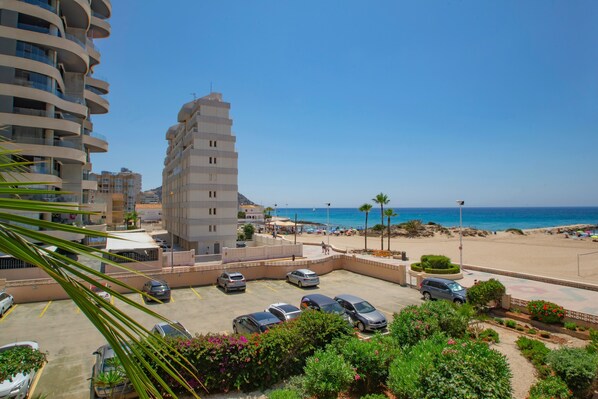 Un bâtiment situé sur la côte, doté d’un espace de stationnement, d’une plage et offrant une vue sur un ciel dégagé.