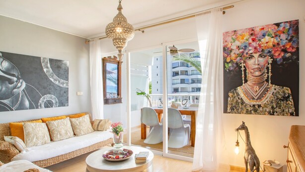 A modern living room with a sofa, a round coffee table, a decorative giraffe, and a painting.