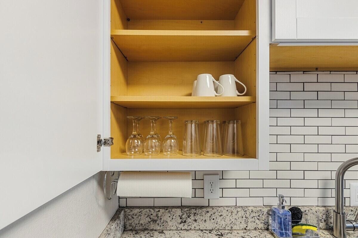 Cucina con mobili bianchi, piano di lavoro in granito e backsplash piastrellato.