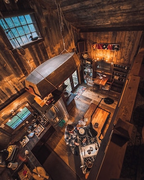 A rustic kitchen with wooden walls, a large window, and a dining area with a table and chairs. - Enjoy this authentic and cozy VT Barn with Brand New Hot Tub (Londonderry)