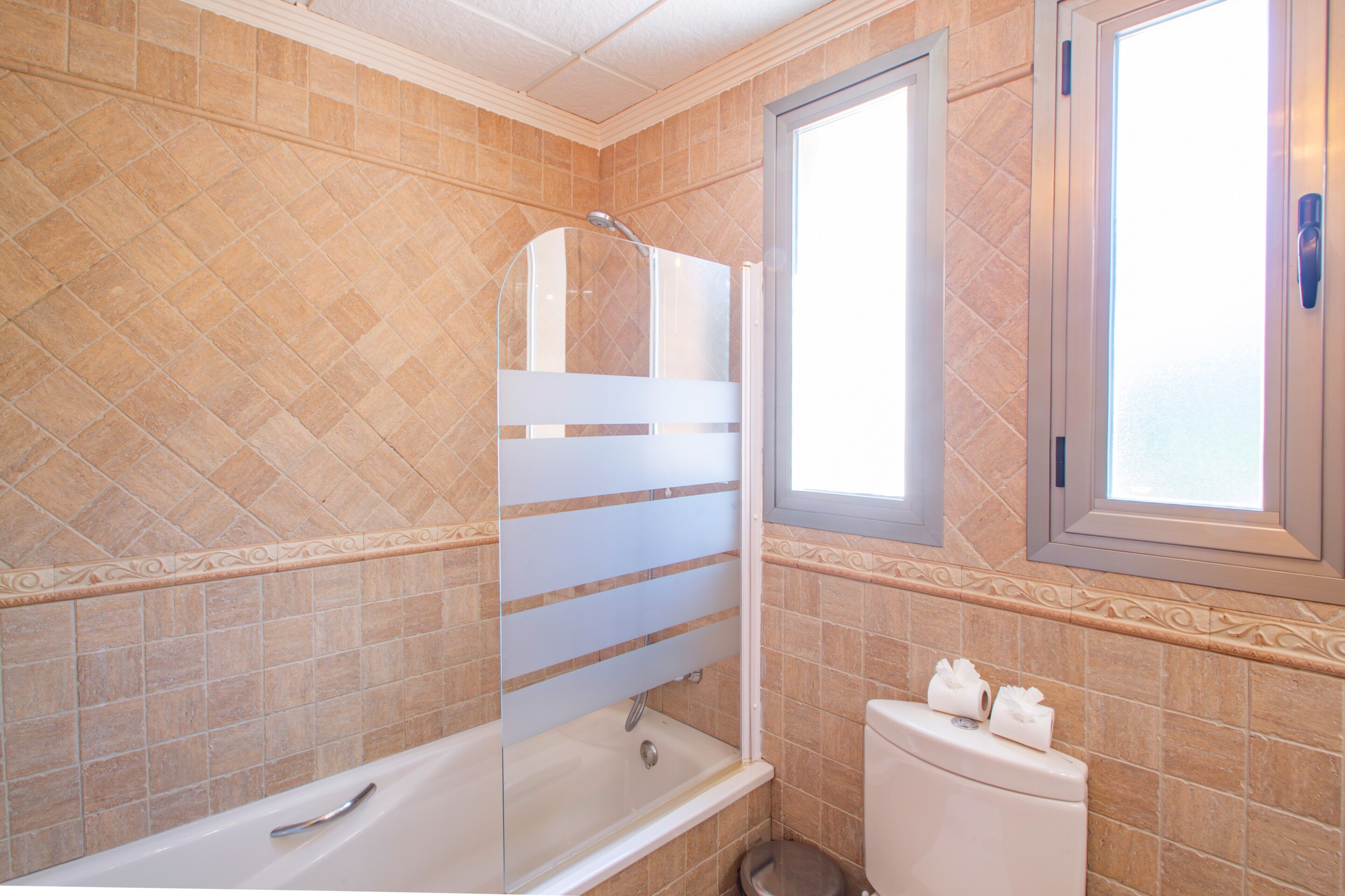 A bathroom with a bathtub, toilet, and a window.