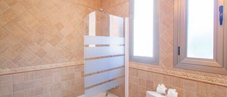 A bathroom with a bathtub, toilet, and a window.