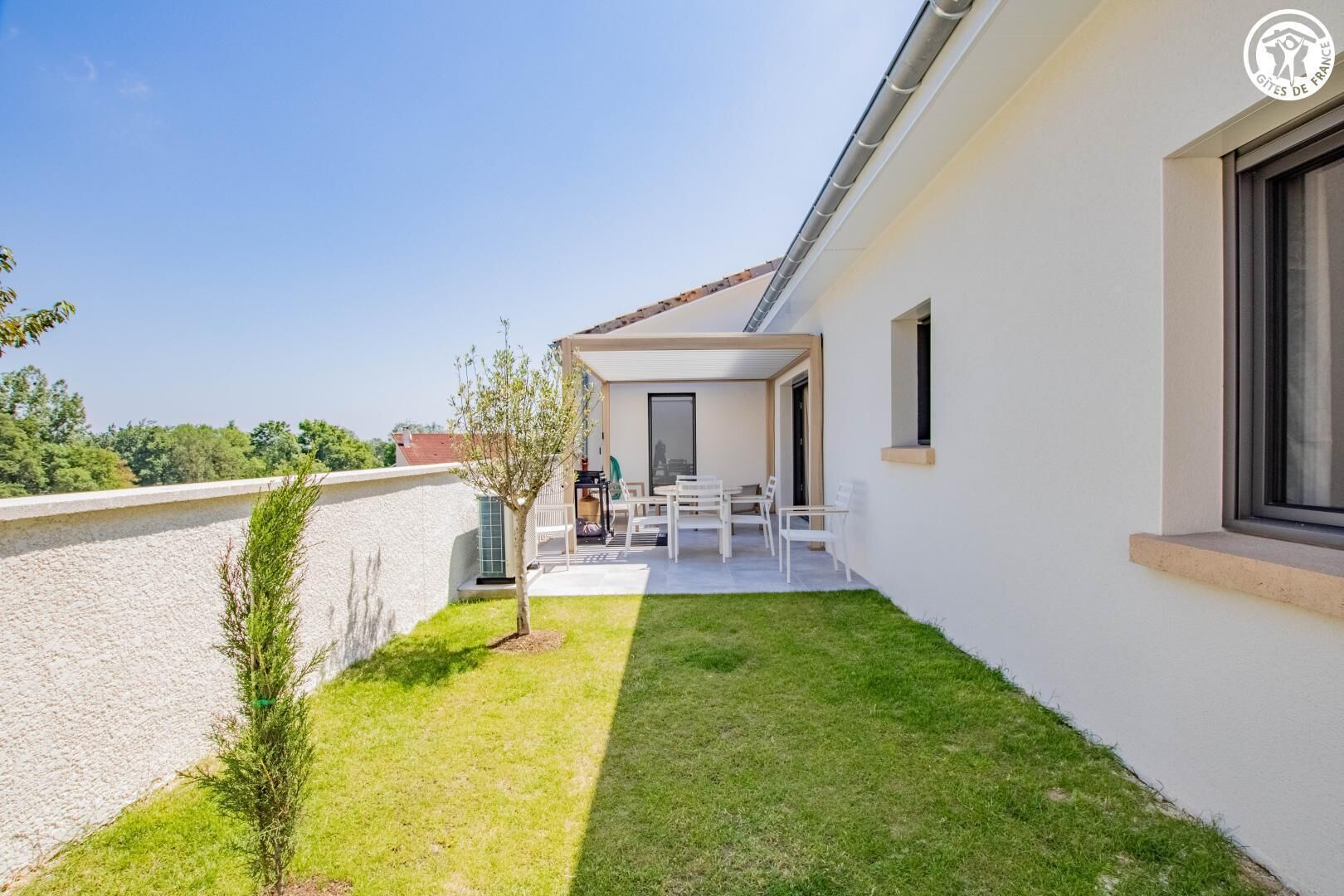A modern building with a covered patio area, a small tree, and a clear view of the surrounding landscape.