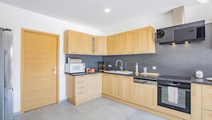 Una cocina moderna con armarios de madera, un refrigerador de acero inoxidable, un microondas, un fregadero, un lavavajillas y un horno.