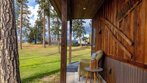 Eine Holzhütte mit überdachter Veranda, einem Korbstuhl und einem kleinen Tisch.