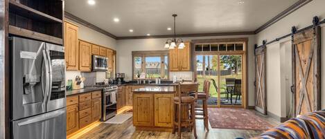A spacious kitchen with wooden cabinets, stainless steel appliances, and a central island with bar stools.