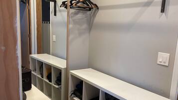 Un dressing avec des étagères blanches, un miroir et un porte-manteau.