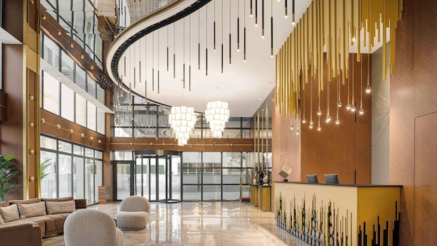 Eine großzügige Lobby mit Empfangsschalter, Sitzgelegenheiten und einer modernen Chandelier.