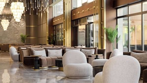 Eine moderne Lobby mit bequemen Sitzmöglichkeiten, spiegelndem Boden und stimmungsvoller Beleuchtung.