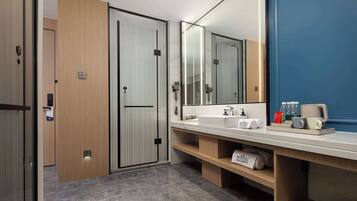 Een moderne badkamer met een grote spiegel, een wastafel en een badkamermeubel. Handdoeken en toiletartikelen liggen op het aanrecht.