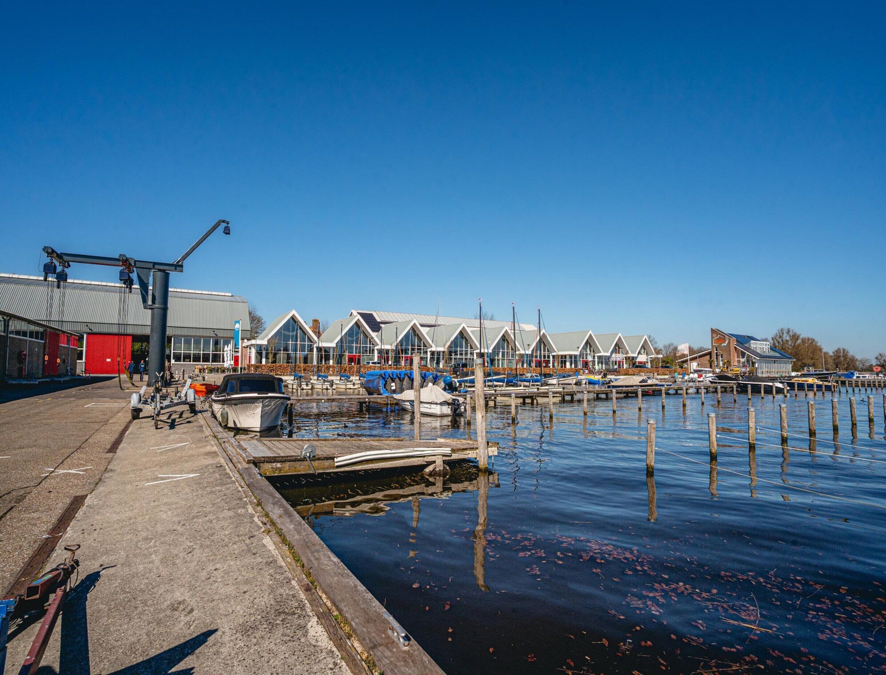 A marina with docked boats, a red building, and a row of white houses with gabled roofs.