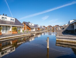 A canal-side residential area with houses, a wooden dock, and calm water.