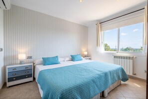 Ein Schlafzimmer mit Bett, Nachttischen, einem Fenster mit Vorhängen und einer Heizung.
