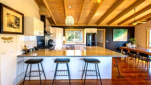 Una cocina moderna con una isla grande, taburetes de bar y una zona de comedor con una mesa y sillas de madera.
