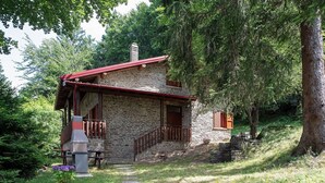 Una casa de piedra con techo rojo, un porche de madera y una chimenea de piedra.