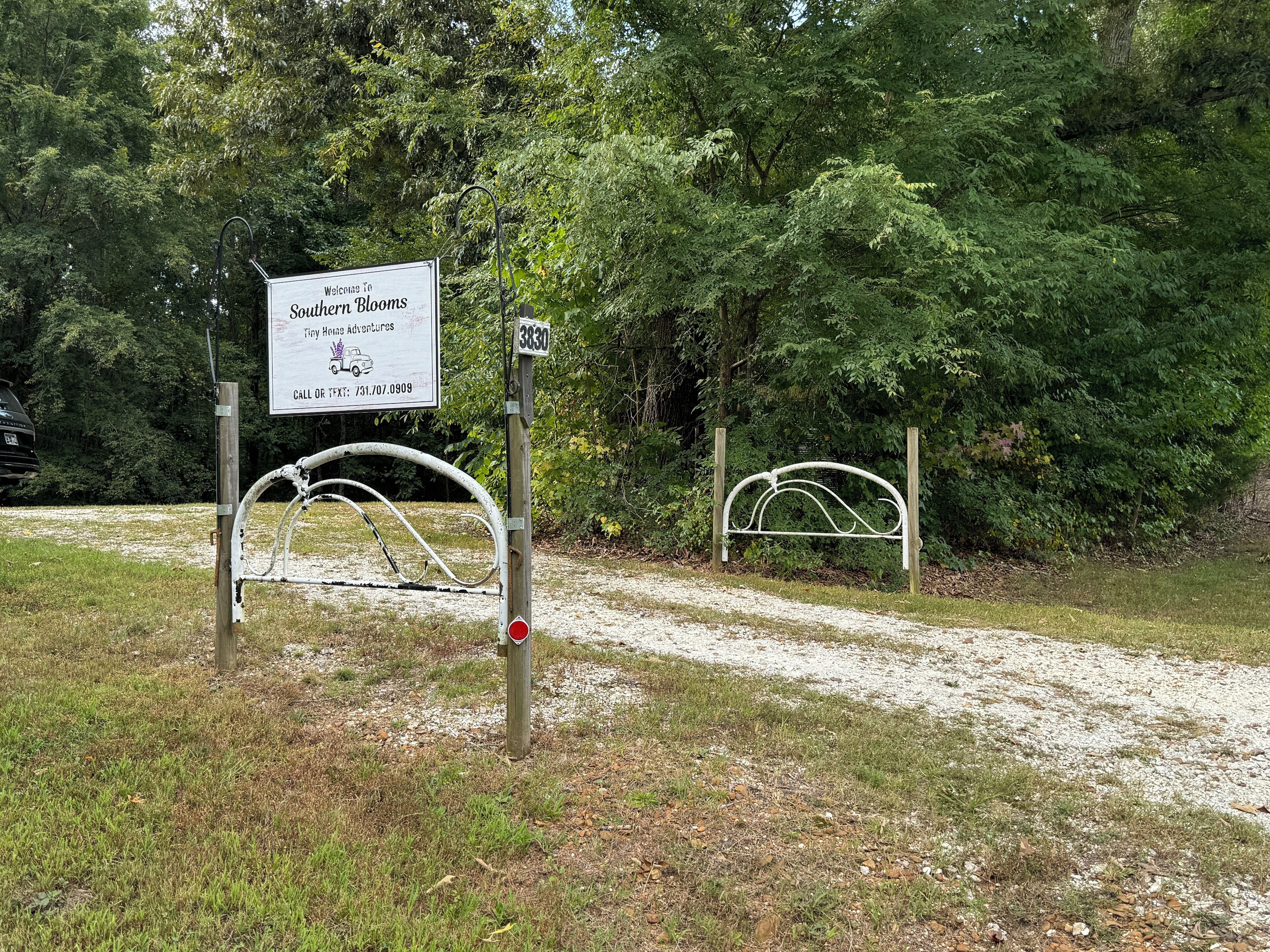 A sign welcoming visitors to Southern Blooms Tiny House Adventures with a contact number.