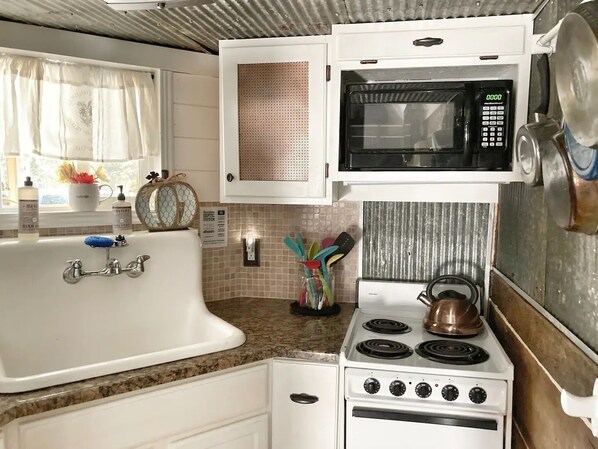 A compact kitchen with a sink, stove, and microwave.