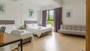A hotel room with two beds, a sofa, a desk, and a window with curtains. - Minima 8  (George Town)