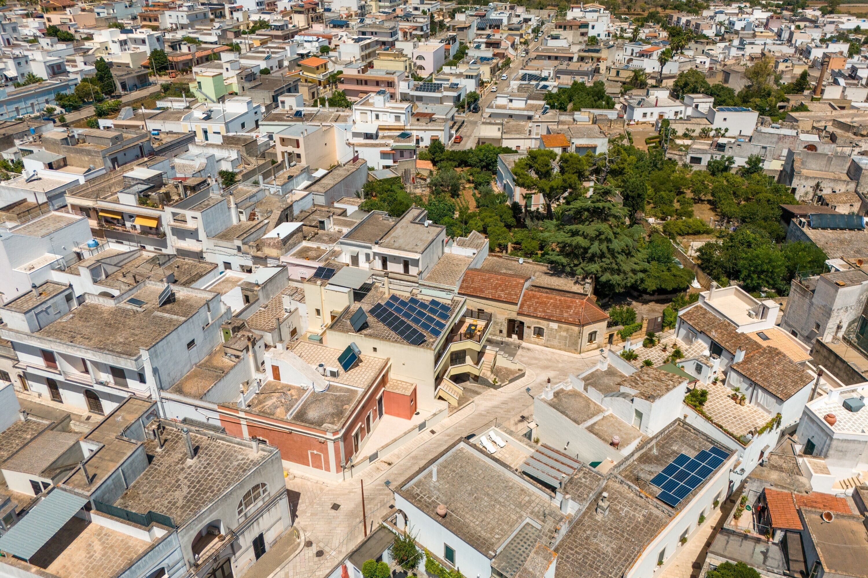 Ein Luftbild eines dicht bebauten Stadtgebiets mit zahlreichen Gebäuden, von denen einige mit Solaranlagen auf den Dächern ausgestattet sind.