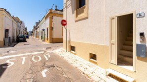 A narrow street with a stop sign, a building with a number 14 sign, and a car parked on the side.