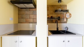 A kitchen with a stove, sink, and cabinets.