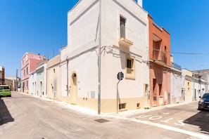 A street with buildings, a stop sign, and a green car. - Apartment 'Casa Donna Sofia' with Private Terrace, Wi-Fi and Air Conditioning (Specchia)