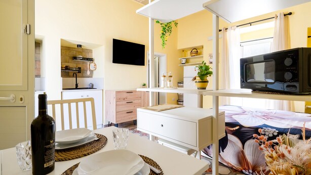 A compact kitchen with a microwave, a television, and a dining area with a table set for two.