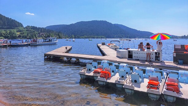 Un quai avec des bateaux, une jetée et une chaîne de montagnes en arrière-plan.