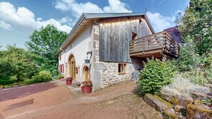 Un bâtiment rustique en pierre, doté d’un balcon en bois, de fenêtres en arc de cercle et de fondations en pierre.