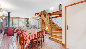 Un coin repas avec une longue table dressée pour le repas, des chaises en bois et une nappe à carreaux.